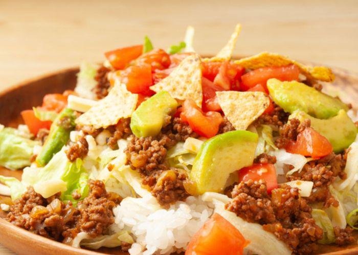 Okinawan Taco Rice, a dish made with a base of rice, topped with ground meat, tomato, avocado, and other taco-inspired toppings